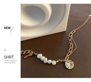 Detail of gold chain bracelet with baroque pearls, key charm and smiley face pendant