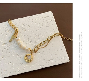 Detailed shot of gold layered bracelet with baroque pearls and smiley face charm