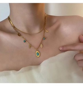 Dettaglio della collana a doppio strato dorata con pendenti a foglia e turchese