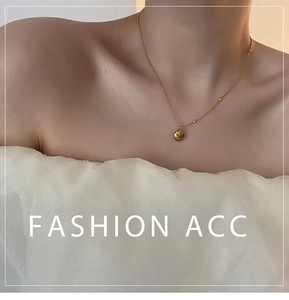 Detailed view of a gold bead pendant necklace worn on neck with a delicate beaded chain