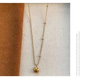 Detail of gold bean necklace showing polished Lucky engraving on sphere pendant
