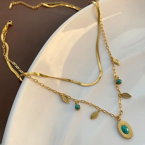 Collana a doppio strato dorata con ciondolo turchese e foglie su vassoio ceramica