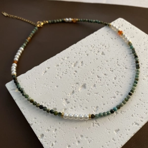 Collar artesanal con piedras naturales verdes y perlas blancas en soporte de piedra