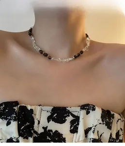 Dettaglio collana asimmetrica con perle nere a goccia e cristalli indossata da una modella
