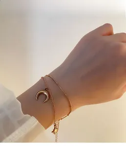 Détail du bracelet double couche avec charms étoile et lune en acier titane doré