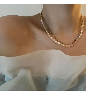 Detail of layered shell bead necklace and delicate gold chain with multi-color accents