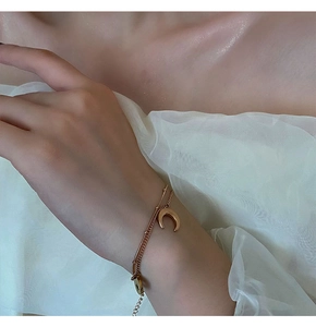 Détail d'un bracelet double couche doré avec pendentif croissant de lune et chaîne à billes