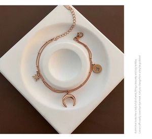 Détail du bracelet double rang or rose avec pendentifs étoile et lune et fermoir