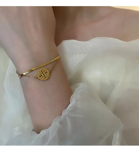 Detail of double-layer gold titanium steel anklet featuring a round hollow pendant on wrist