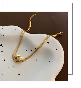 Close-up of double-layered gold titanium steel anklet with circular character pendant