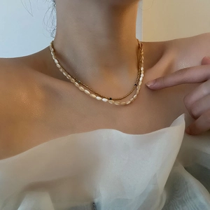 Elegant layered gold bead and white shell pearl necklace worn on collarbone