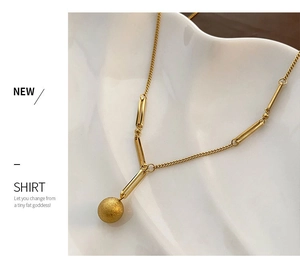 Gros plan sur collier en titane doré avec pendentif sphérique givré sur céramique