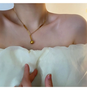 Détail du collier en titane doré élégant avec perle givrée sur un mannequin