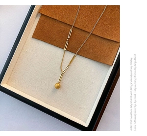 Détail du collier en titane doré avec pendentif perle mate et maillons rectangulaires