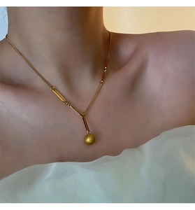 Gros plan du collier en titane doré avec perle givrée et pendentif géométrique élégant