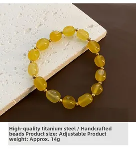 Détail d'un bracelet en pierre naturelle jaune avec chaîne ajustable en acier titane doré