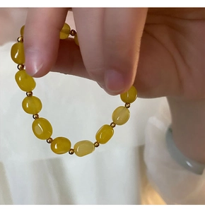 Détail des perles en pierre jaune translucide lisse avec des séparateurs dorés raffinés