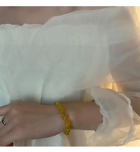 Détail d'un bracelet en perles de pierre naturelle jaune avec entretoises dorées au poignet