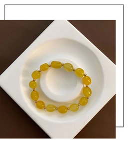 Détail d'un bracelet en pierre naturelle jaune avec entretoises dorées sur plateau