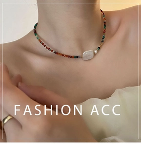Close-up of a colorful beaded necklace featuring a large white baroque pearl on the neck