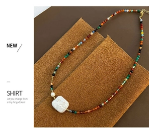 Macro shot of colorful natural stone beads with a white baroque pearl on vintage necklace