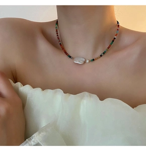 Close-up of a colorful beaded necklace featuring a baroque pearl on a woman's neck