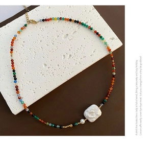 Detail of colorful beaded necklace with baroque pearl and golden lobster clasp