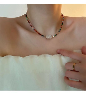 Detail of colorful beaded necklace with a central Baroque pearl on a female model