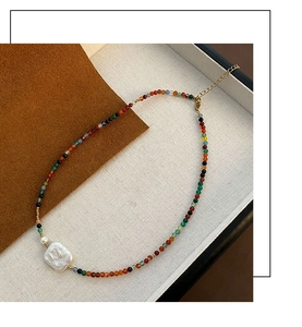 Macro shot of colorful beads with a Baroque pearl and gold lobster clasp necklace