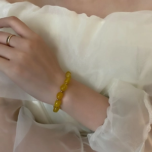 Bracelet élégant en pierre naturelle jaune avec perles dorées porté par un mannequin