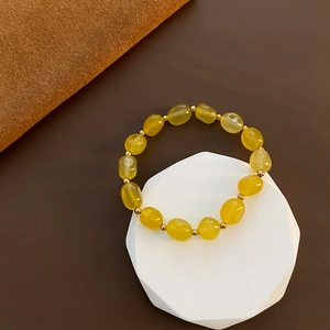 Élégant bracelet en pierre naturelle jaune avec accents dorés sur un support moderne