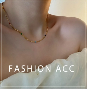 Detail of gold beaded collar necklace with colorful charms on female neck