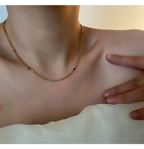 Detailed view of titanium steel necklace with colorful beads on a gold chain worn by a model