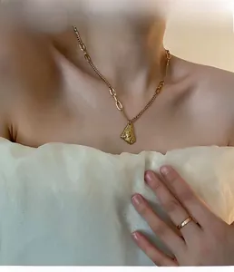 Detail of vintage gold necklace with embossed face pendant and white bead accent