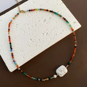 Baroque pearl necklace with colorful beads and gold adjustable chain on stone background