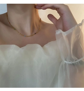 Detailed view of a gold titanium necklace with colorful beads on a model's collarbone