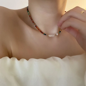 Elegant baroque pearl necklace with multicolor beads worn by a model in warm light