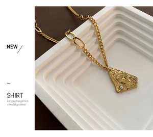 Close-up of a gold titanium necklace featuring a portrait relief pendant and a small pearl