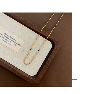 Close-up of golden necklace with colorful beads on a wooden tray for a luxury look