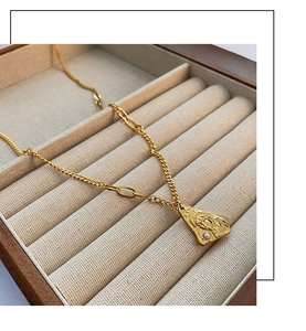 Detailed close-up of gold titanium necklace with female face relief pendant and pearl