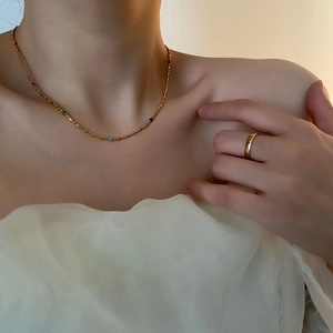 Chic gold titanium steel necklace with colorful beads on a model with white ruffled shirt