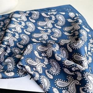 Macro shot of blue paisley silk scarf with elegant satin luster and soft draped texture