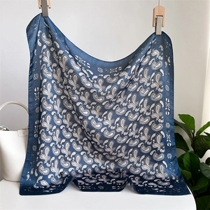Navy blue paisley silk scarf styled with a white handbag and lush green plants