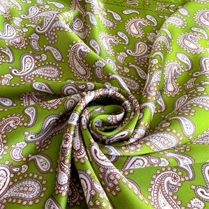 Macro detail of silky paisley fabric in bright green showing soft texture and drape
