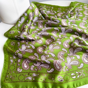 Detailed view of the vibrant green silk scarf featuring classic paisley patterns