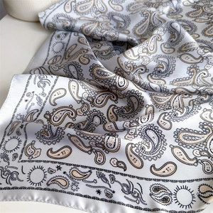Detail of silk scarf with black and gold paisley patterns and satin luster texture