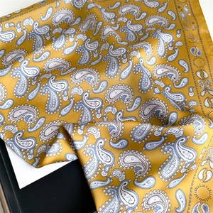 Close-up of yellow silk scarf featuring blue paisley patterns and sun sun-symbols