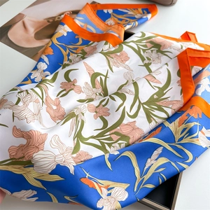 Gros plan détaillé du foulard en soie à fleurs avec bordures orange vif