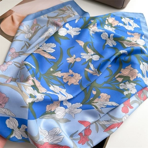 Gros plan d'un foulard en soie bleue avec motifs iris et texture satinée douce