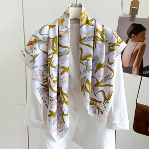 Détail d'un foulard en soie à motif floral drapé sur une veste de costume blanche